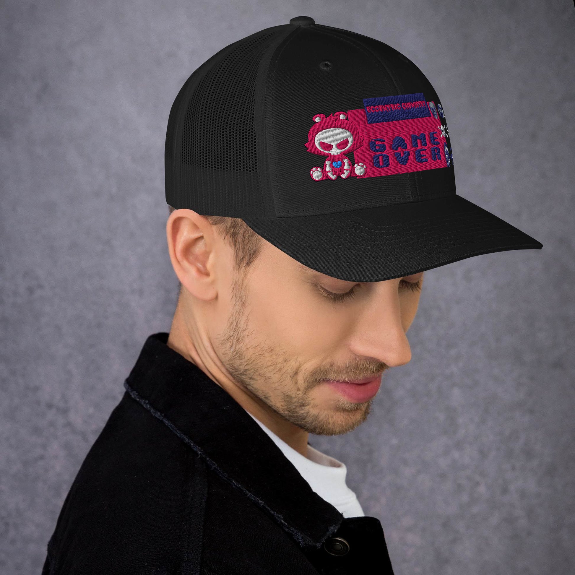 Black pixel panic experiment trucker cap with mesh back and flat brim, featuring a retro-inspired design from Eccentric Chemistry.